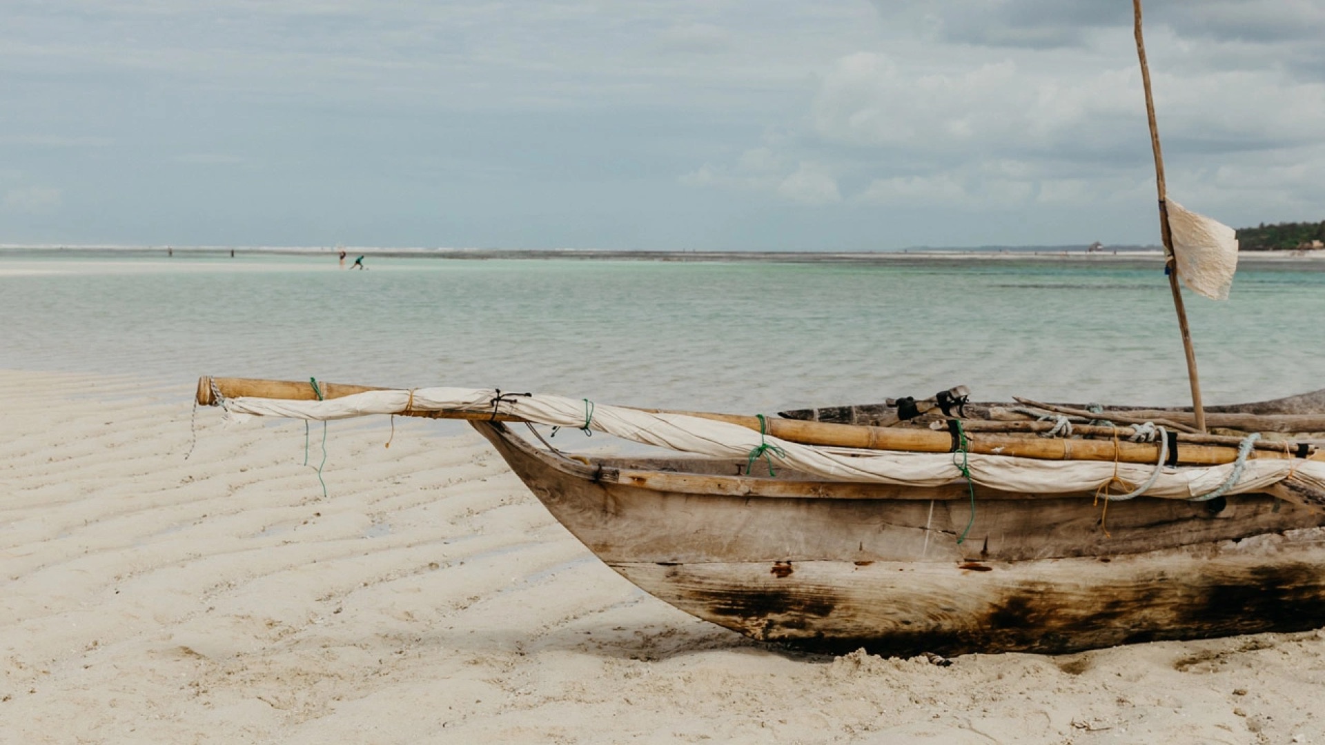 A traditional dhow drawn up on the sand on a Zanzibar beach